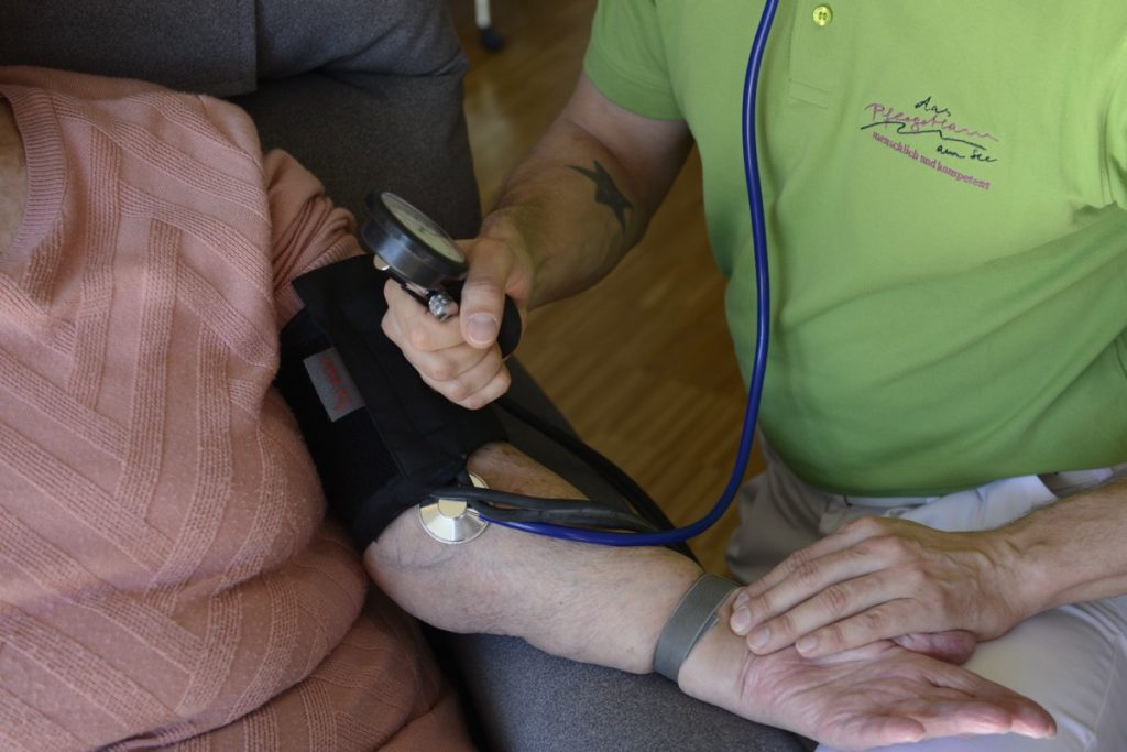 Blutdruckmessung am Arm durch Pflegekraft des Pflegeteam am See
